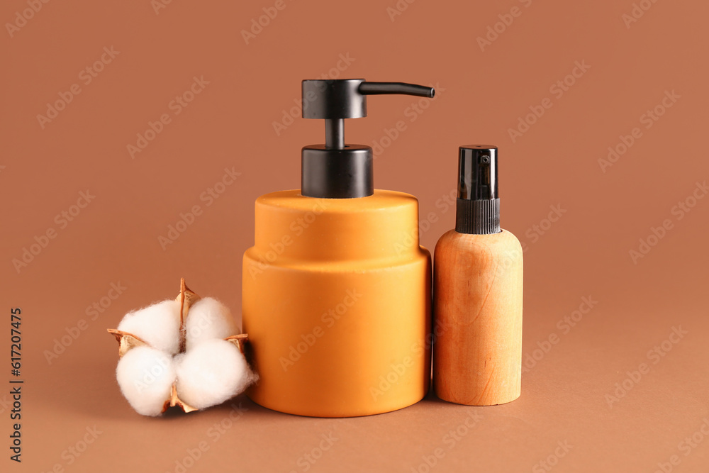 Bottles of cosmetic products and cotton flower on color background