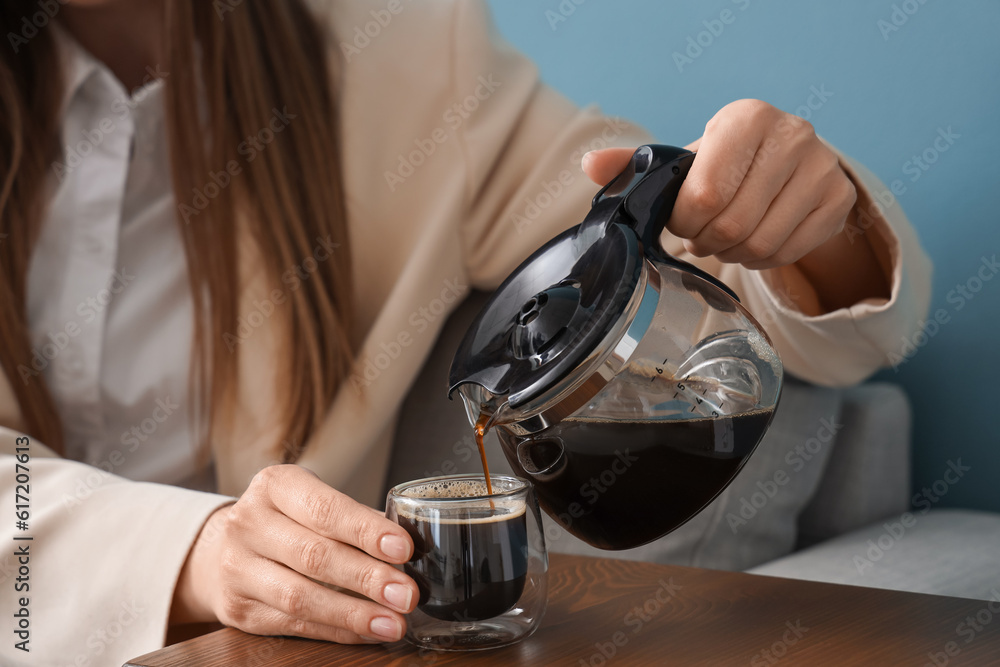 Woman pouring coffee from pot into glass on table