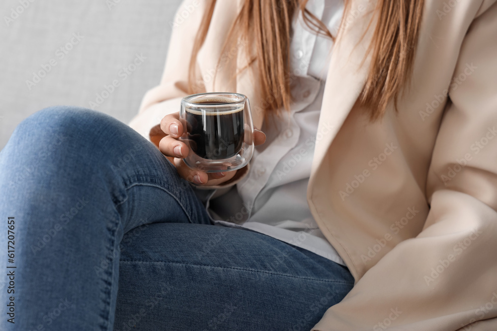 Woman sitting on sofa with glass of delicious coffee