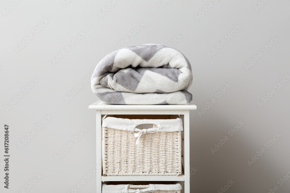 New soft folded blanket on shelving unit on light background