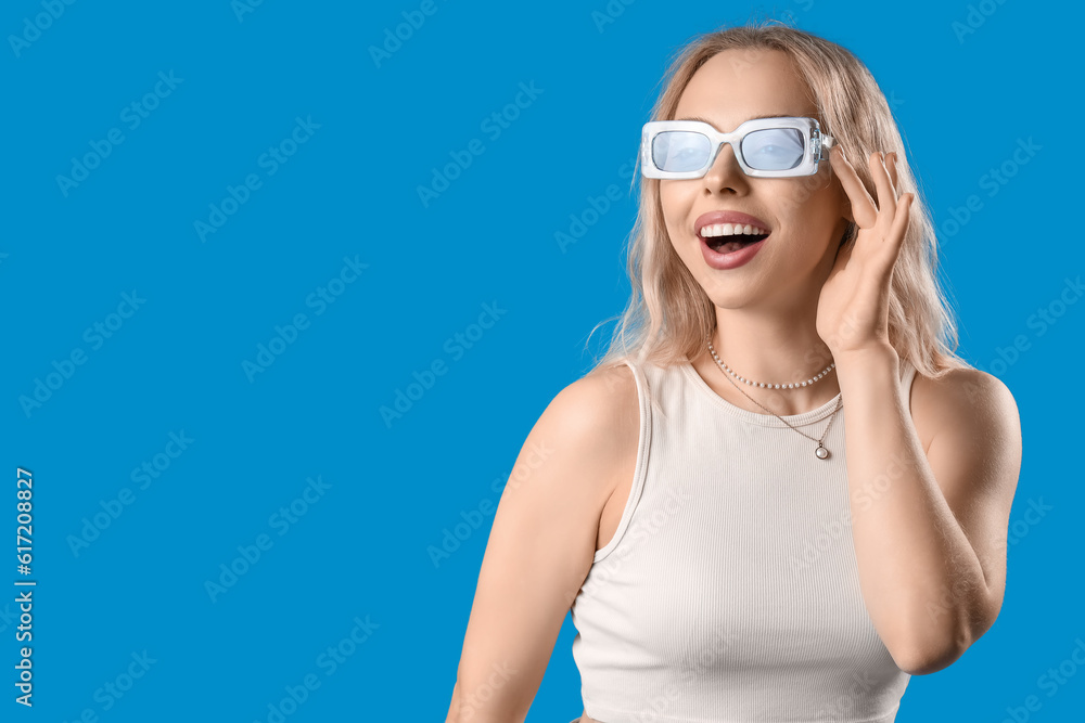 Young woman in stylish sunglasses on blue background