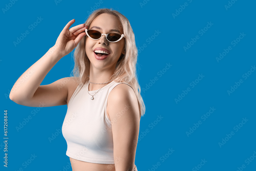 Young woman in stylish sunglasses on blue background