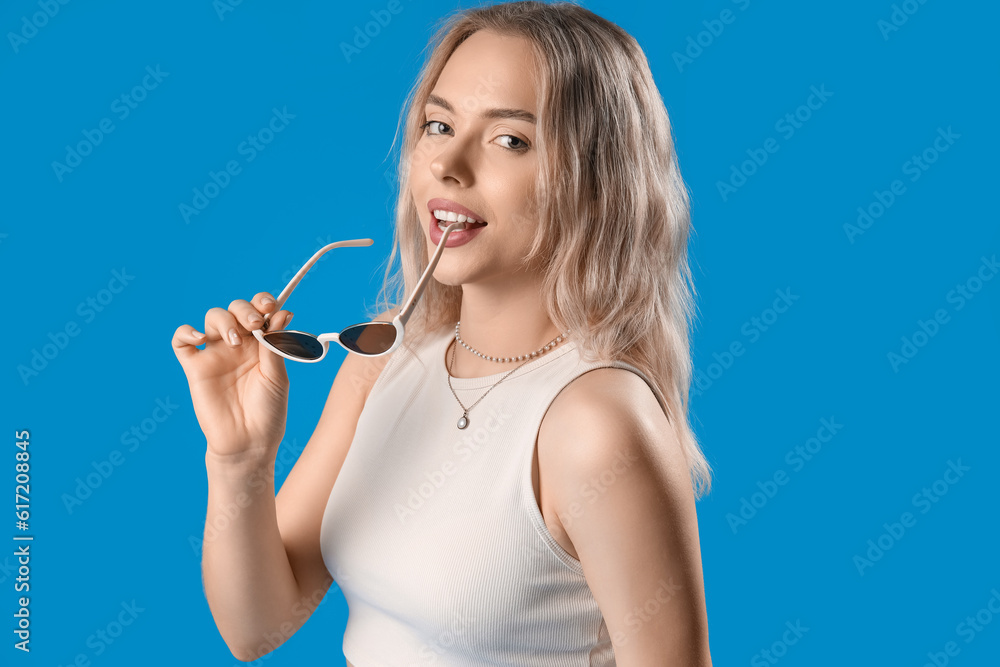 Young woman with stylish sunglasses on blue background