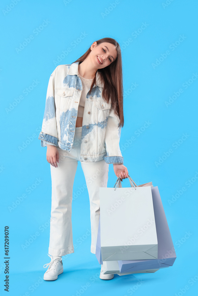 Young woman with shopping bags on blue background