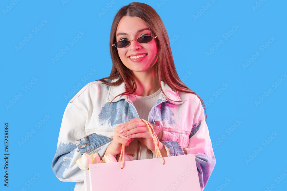 Young woman with shopping bags on blue background