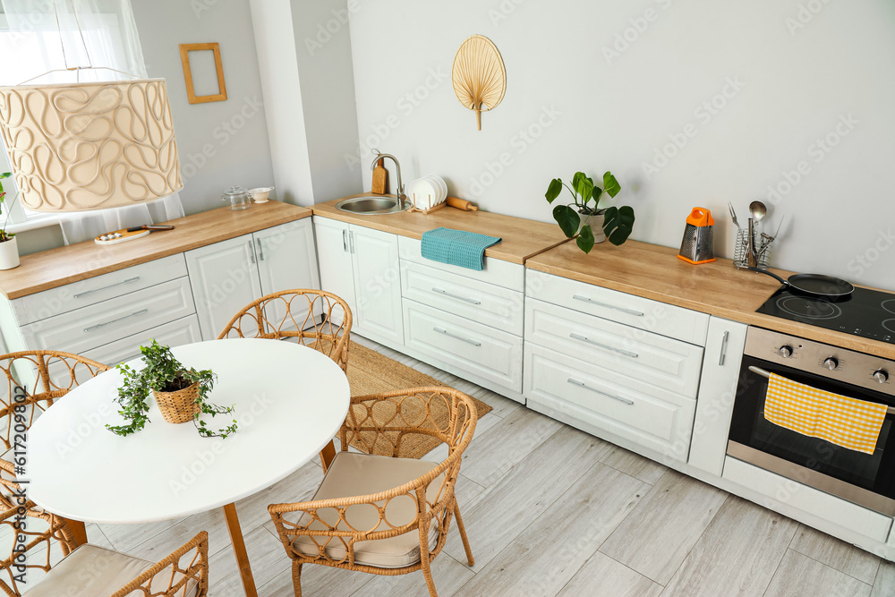 Interior of light kitchen with white counters, electric oven and dining table