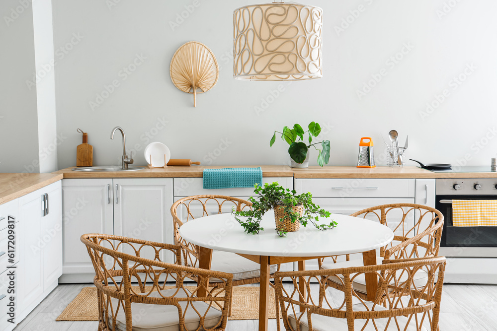 Interior of light kitchen with white counters, electric oven and dining table