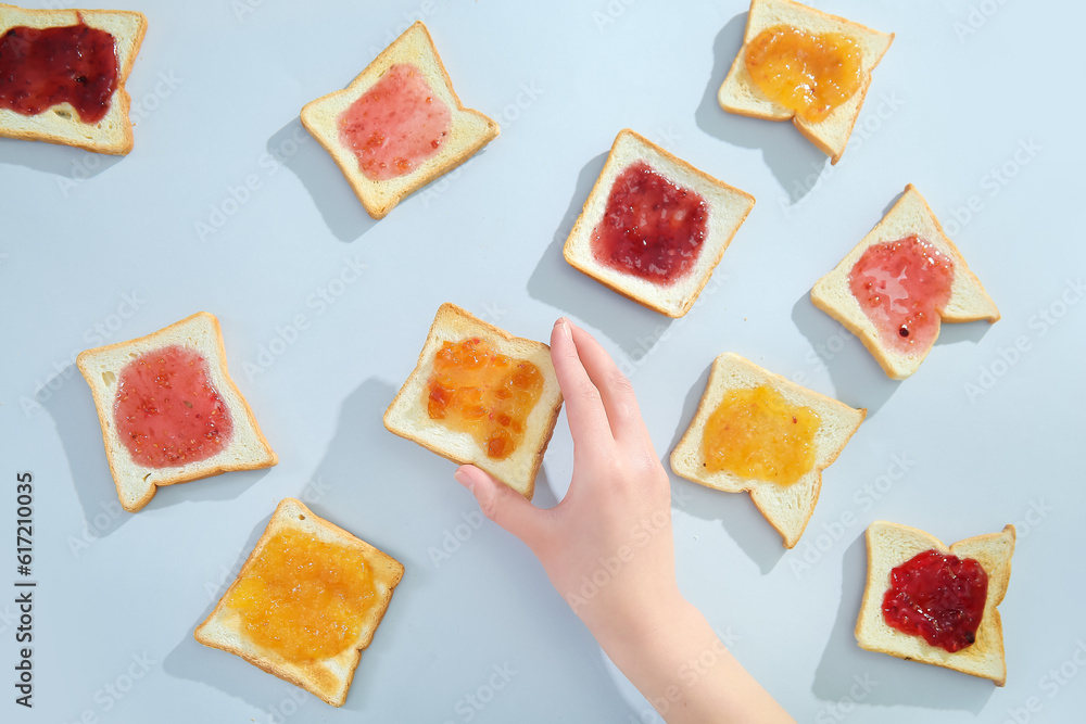 Female hand and delicious toasts with different jams on light background