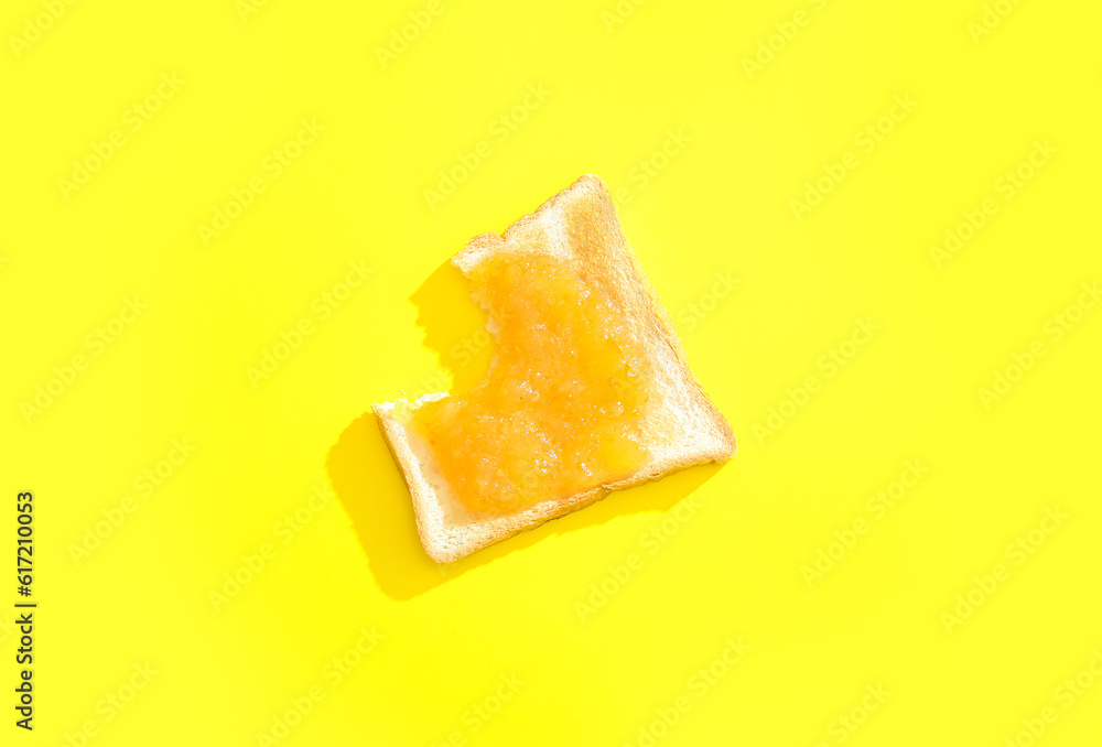 Bitten toast with sweet jam on yellow background