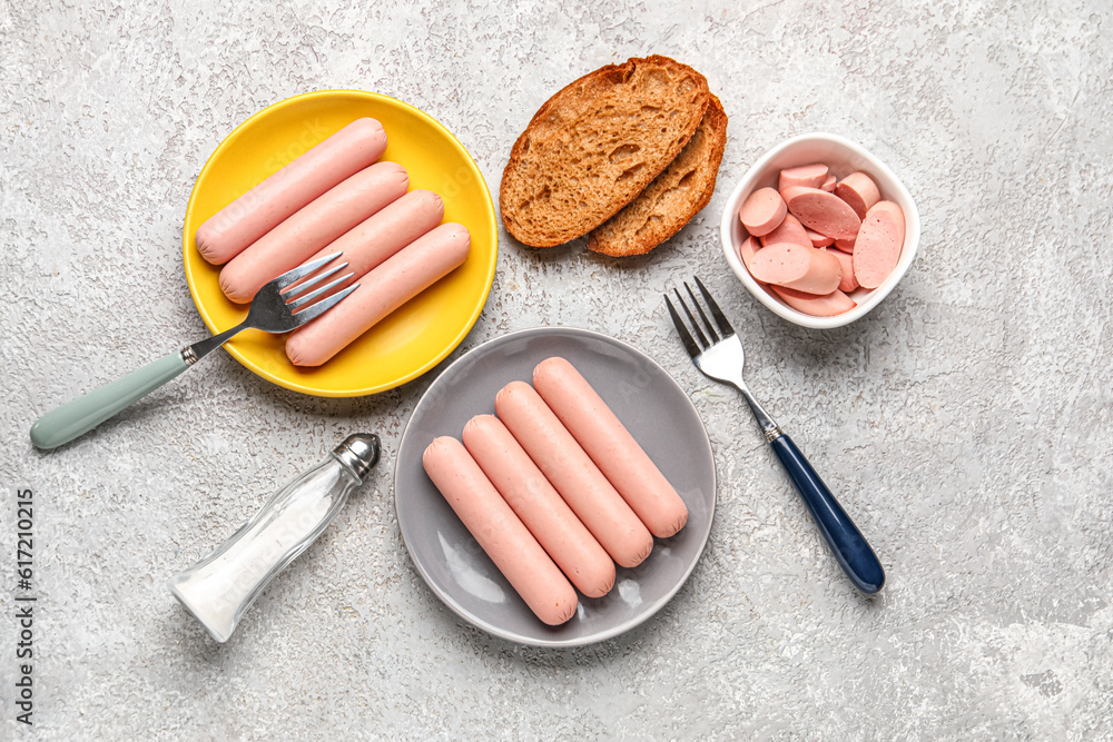 Bowl and plates with tasty thin sausages on grey background