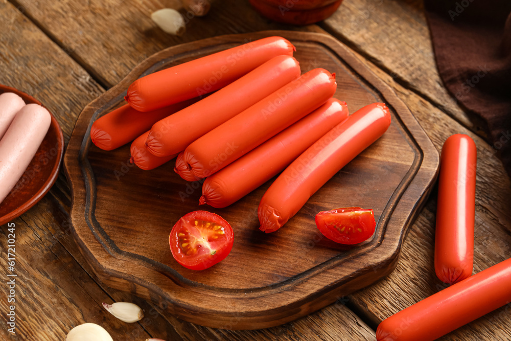 Board with tasty thin sausages on wooden background