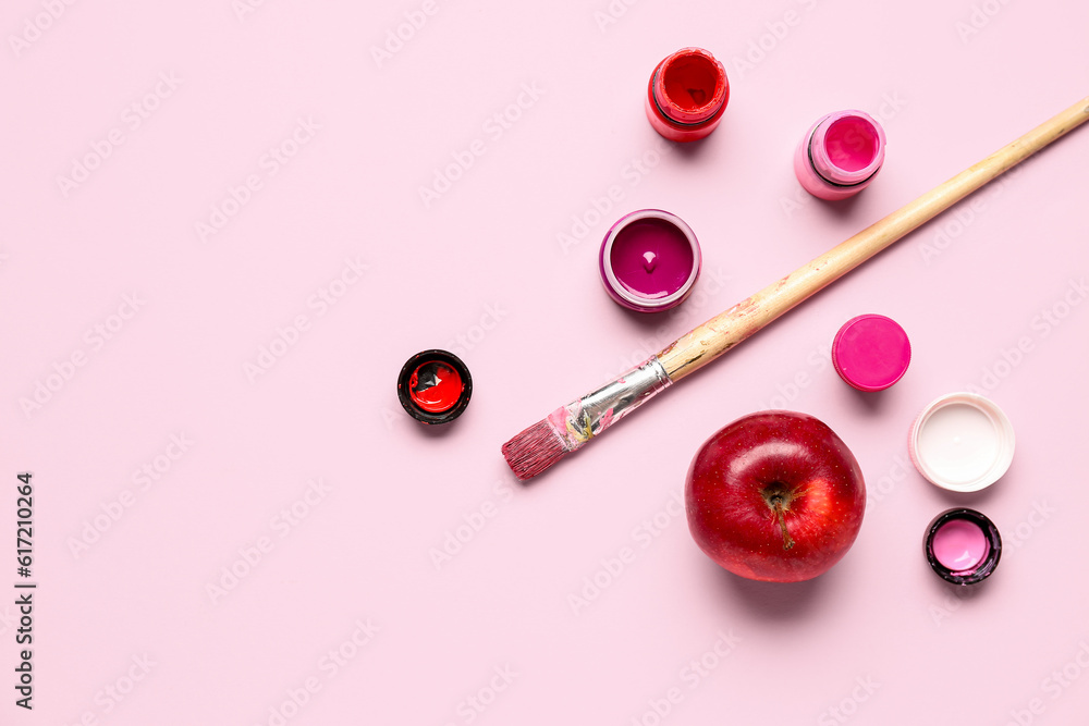 Brush, bottles with different shades of pink paint and apple on color background