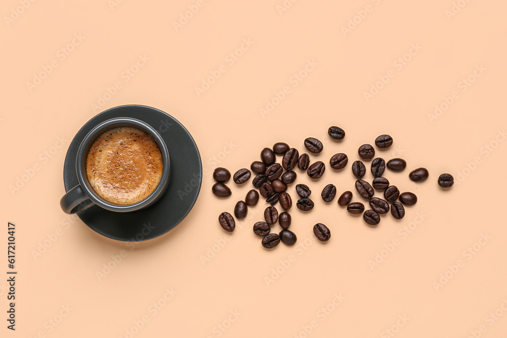 Cup of hot espresso and coffee beans on beige background