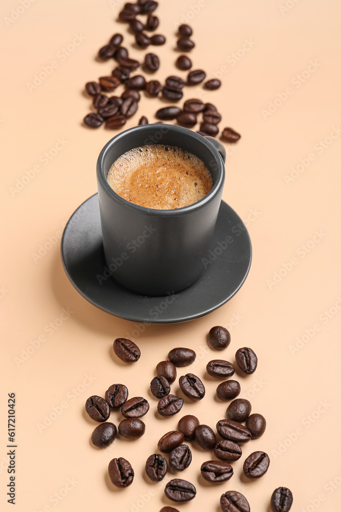 Cup of hot espresso and coffee beans on beige background