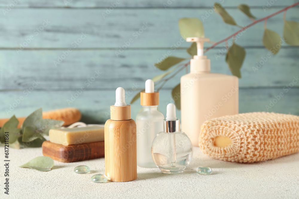 Bottles of cosmetic products, soap and sponge on color background