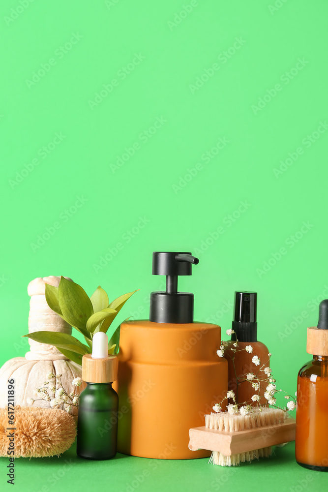 Bottles of cosmetic products, brushes, herbal bag and gypsophila flowers on green background