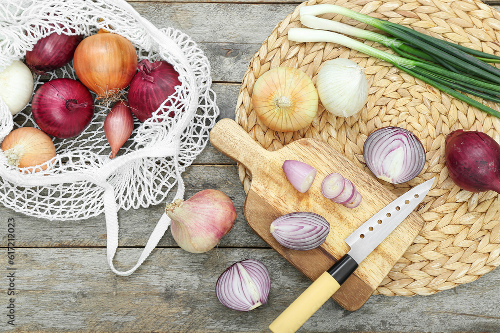 Board and string bag with different kinds of onion on brown wooden background