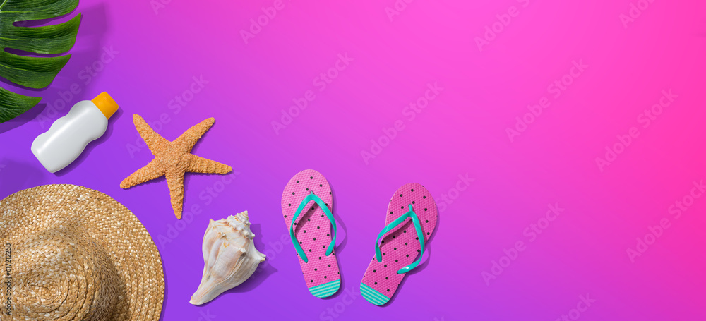 Summer concept with a straw hat, sunblock, starfish, beach sandals and shell overhead view