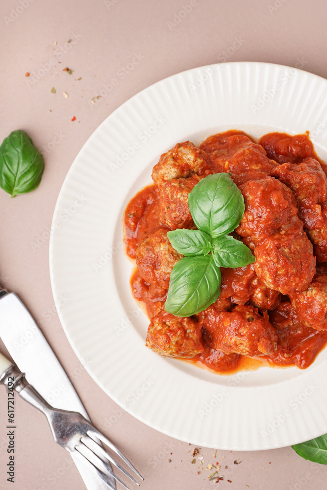 Plate of tasty meat balls with sauce on beige background