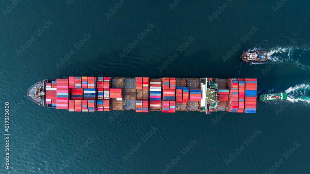 Aerial top view of cargo ship carrying container and running with tug boat for import export goods f