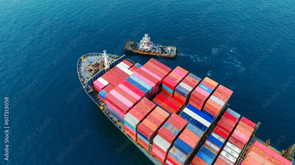 Aerial top view of cargo ship carrying container and running with tug boat for import export goods f