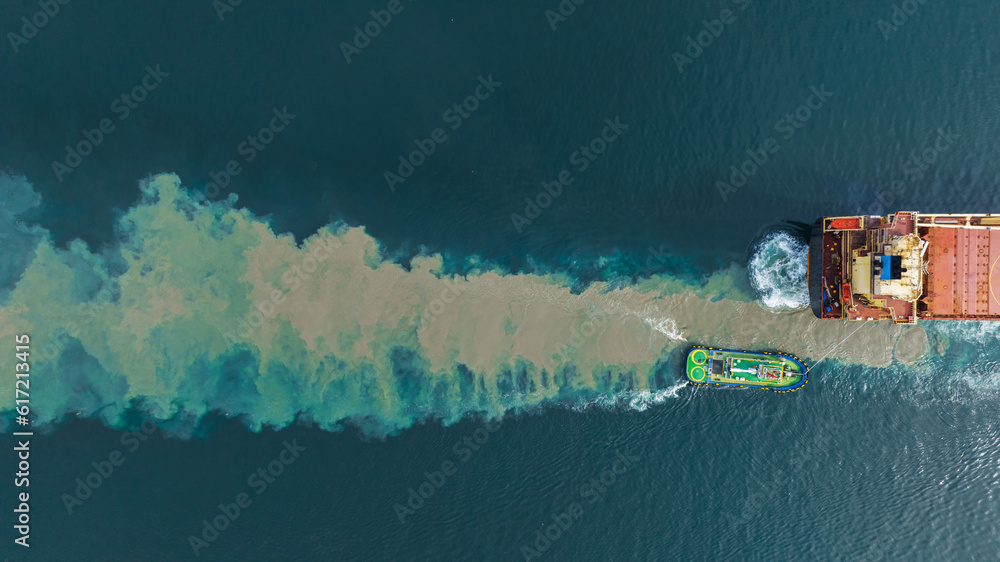 Aerial top view of cargo ship carrying container and running with tug boat for import export goods f