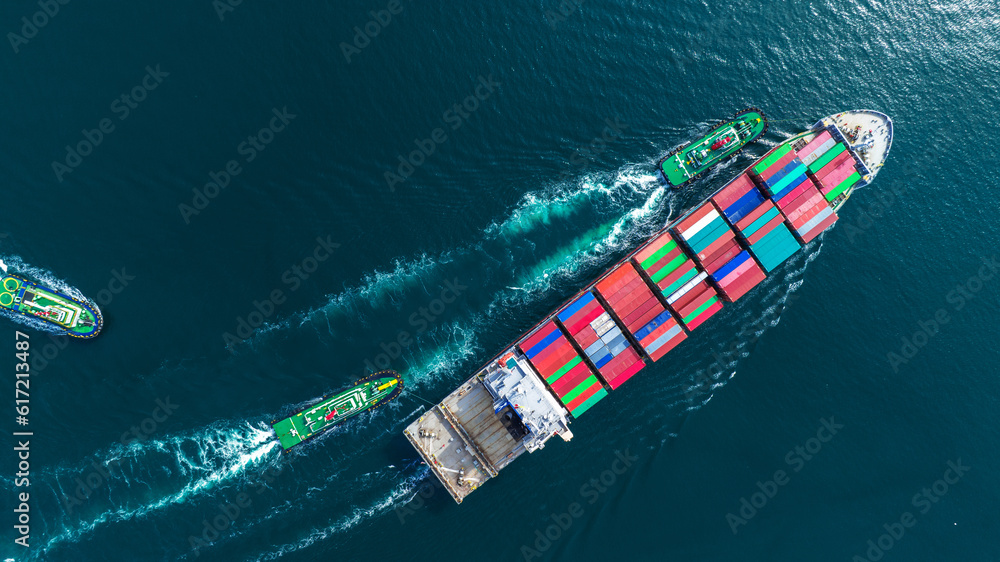 Aerial top view of cargo ship carrying container and running with tug boat for import export goods f