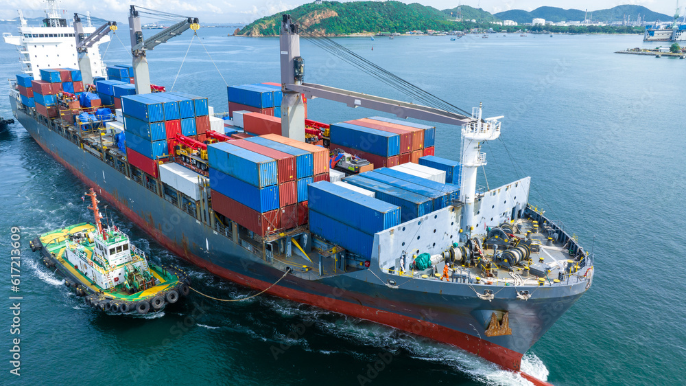 Aerial front view of cargo ship carrying container and running with tug boat for import export goods