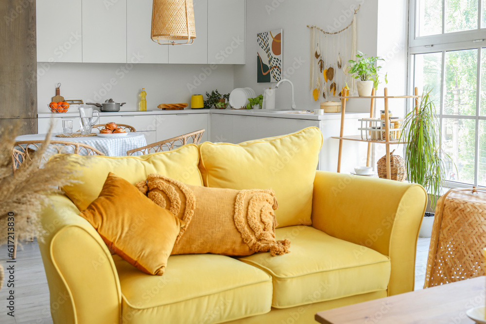 Stylish yellow sofa in interior of light open space kitchen