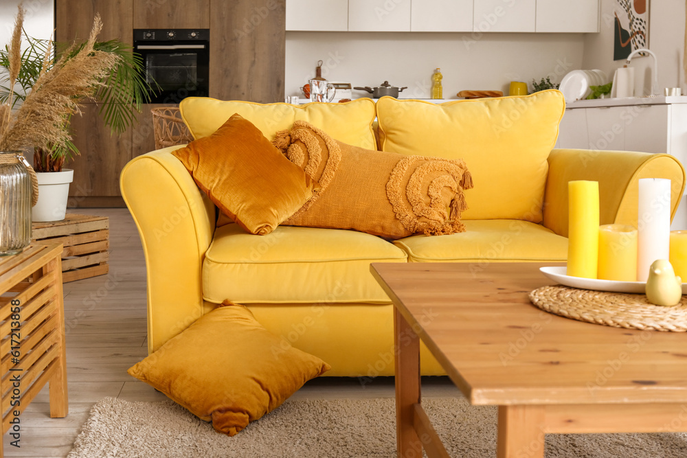 Interior of light open space kitchen with yellow sofa and wooden coffee table