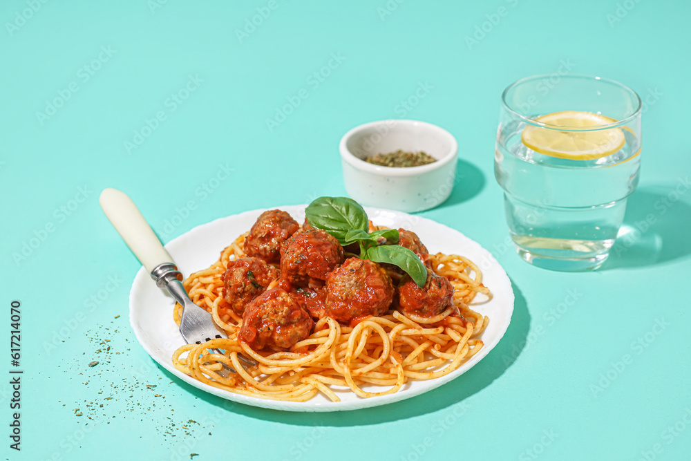 Plate of boiled pasta with tomato sauce and meat balls on blue background