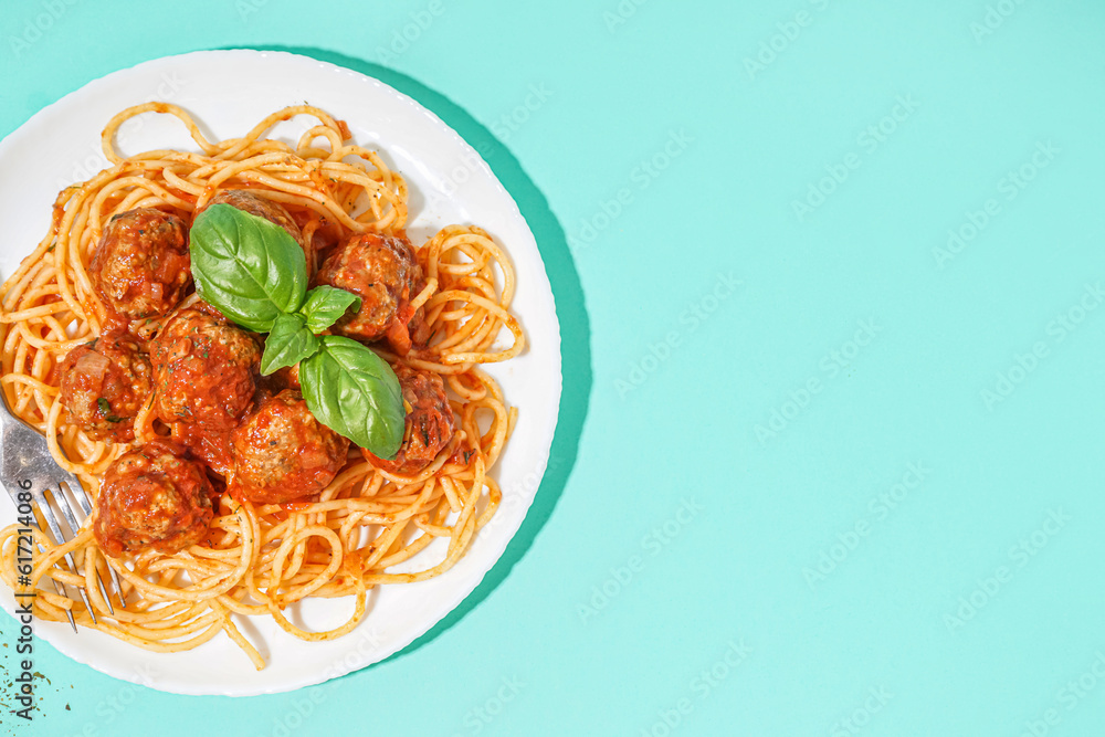 Plate of boiled pasta with tomato sauce and meat balls on blue background