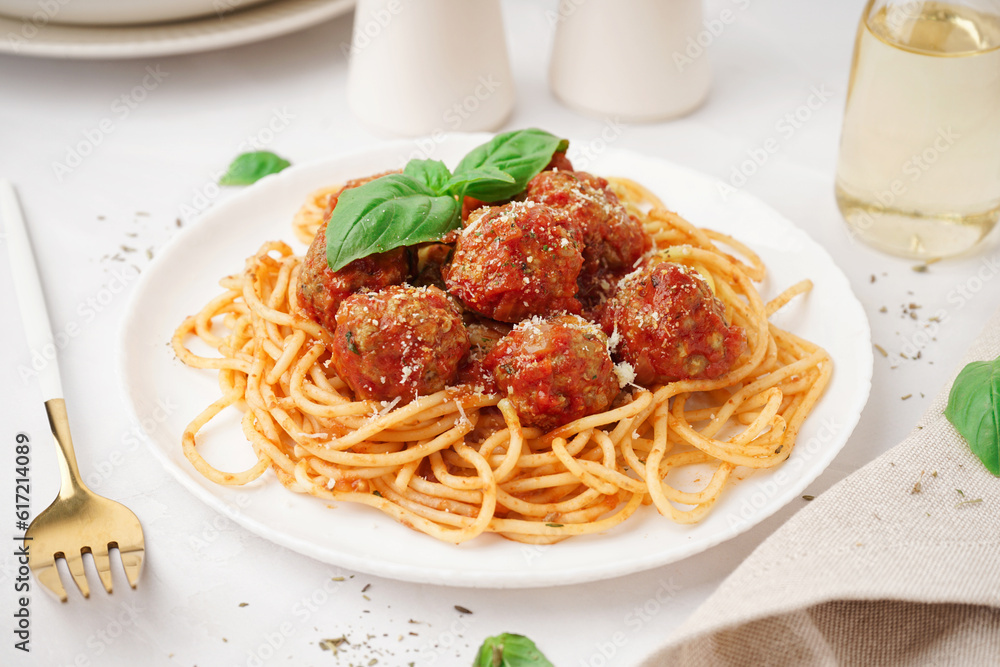 Plate of boiled pasta with tomato sauce and meat balls on white table