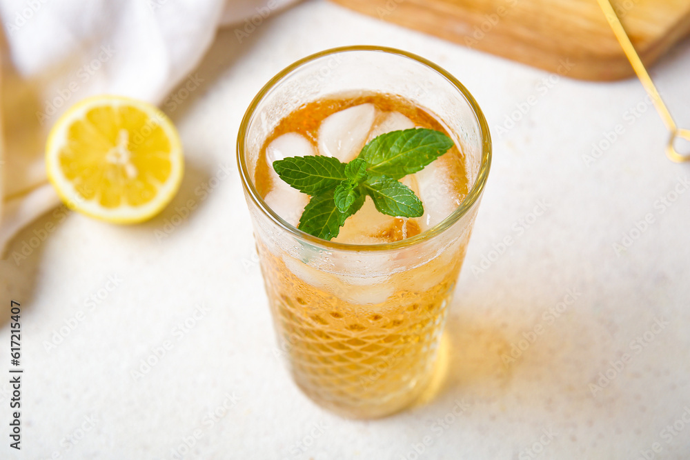 Glass of ice tea with mint and lemon on white background