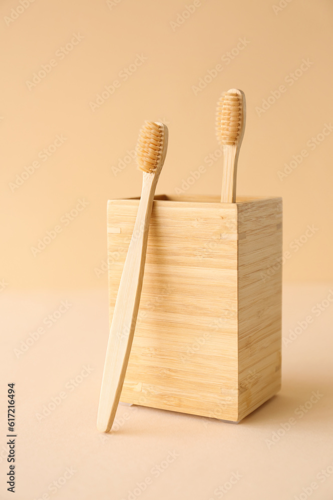 Bamboo tooth brushes and holder on beige background