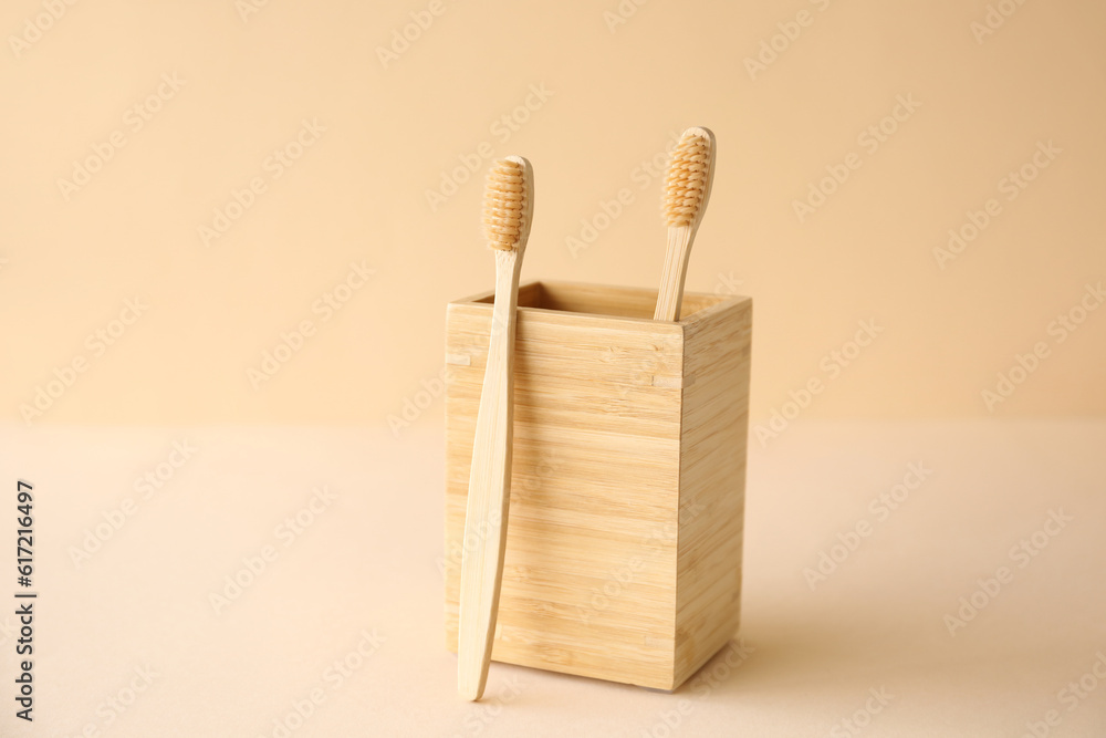 Bamboo tooth brushes and holder on beige background