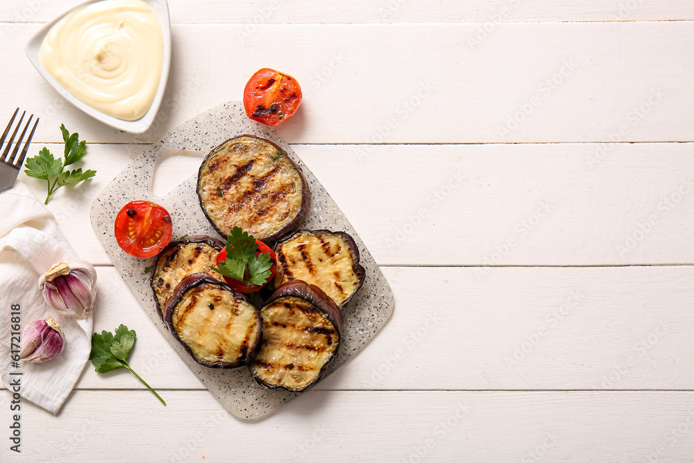 Delicious grilled eggplants, sauce and tomatoes on white wooden background