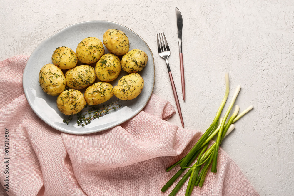 Plate of boiled baby potatoes with dill and green onion on white background