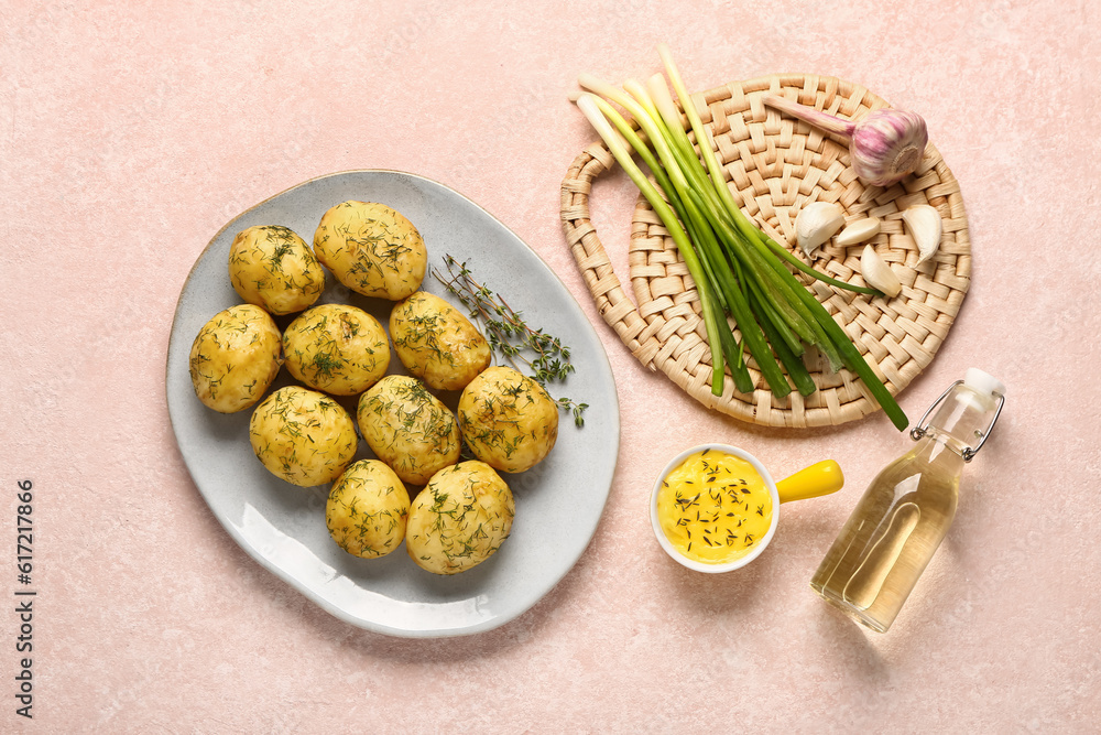 Plate of boiled baby potatoes with dill and green onion on pink background