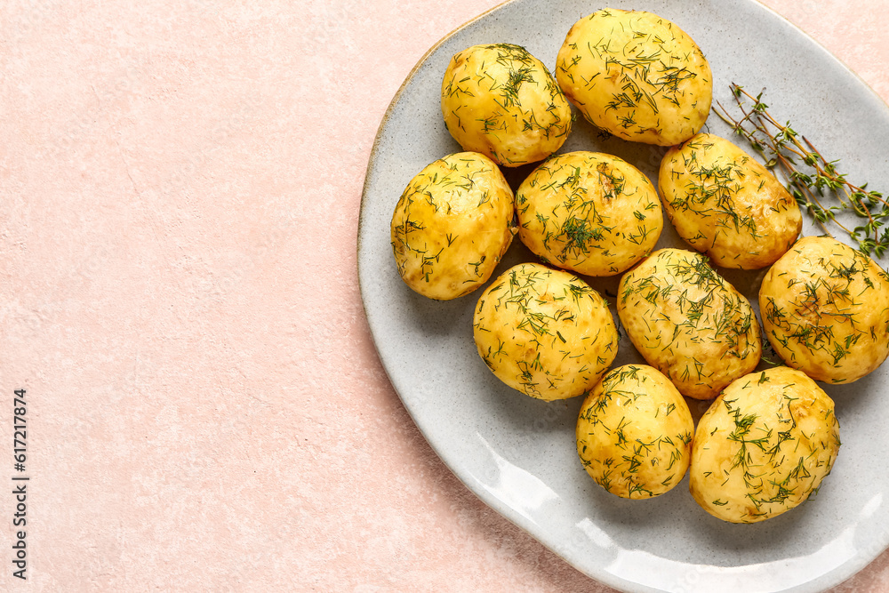 Plate of boiled baby potatoes with dill on pink background