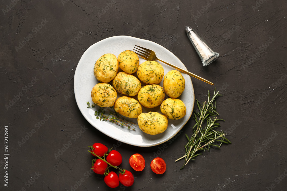 Plate of boiled baby potatoes with dill and rosemary on black background