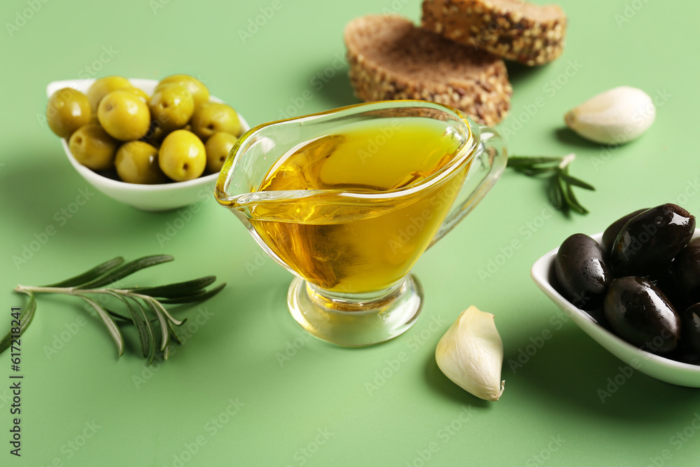 Gravy boat with fresh olive oil on green background