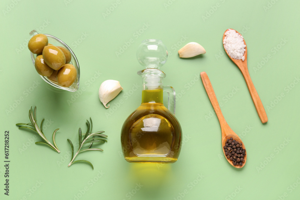 Gravy boat with ripe olives and jug of oil on green background