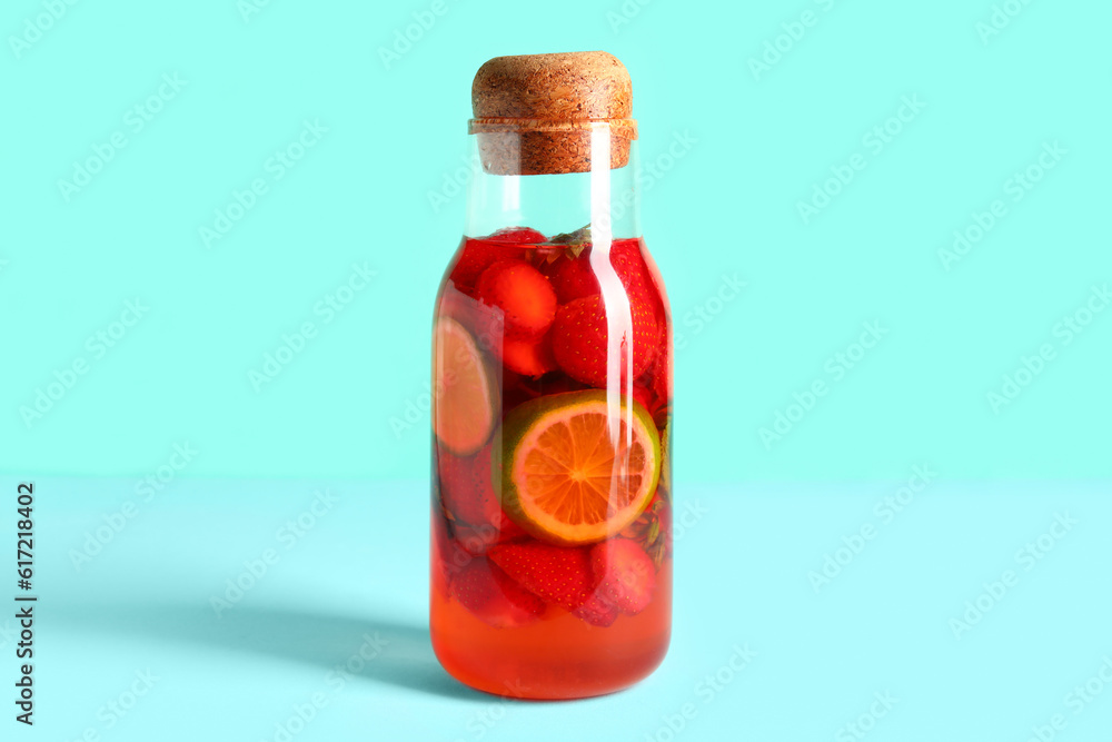 Bottle of infused water with strawberry and lime on blue background