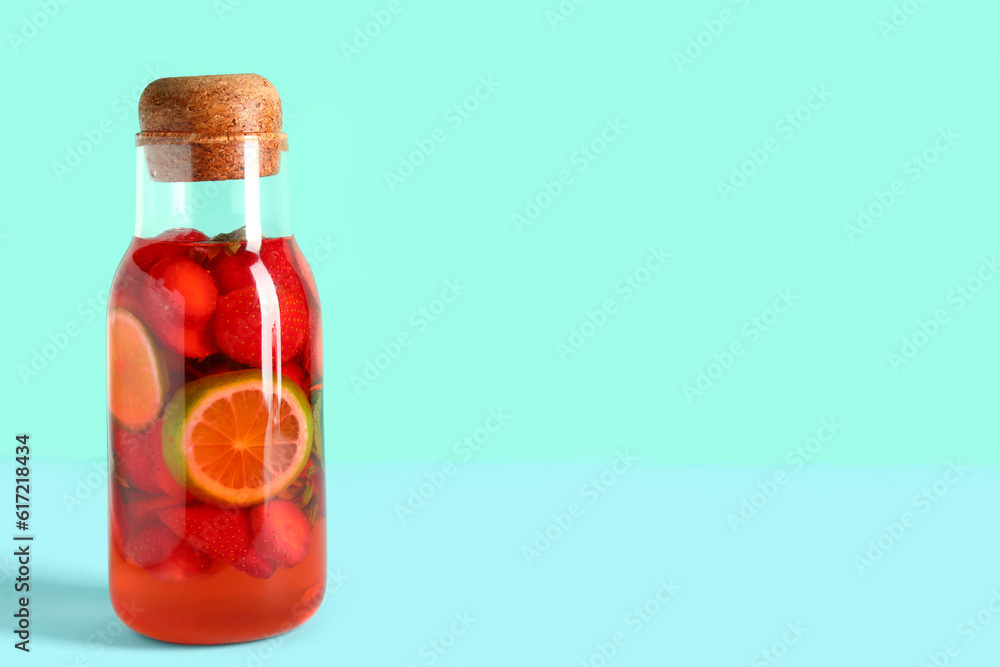 Bottle of infused water with strawberry and lime on blue background