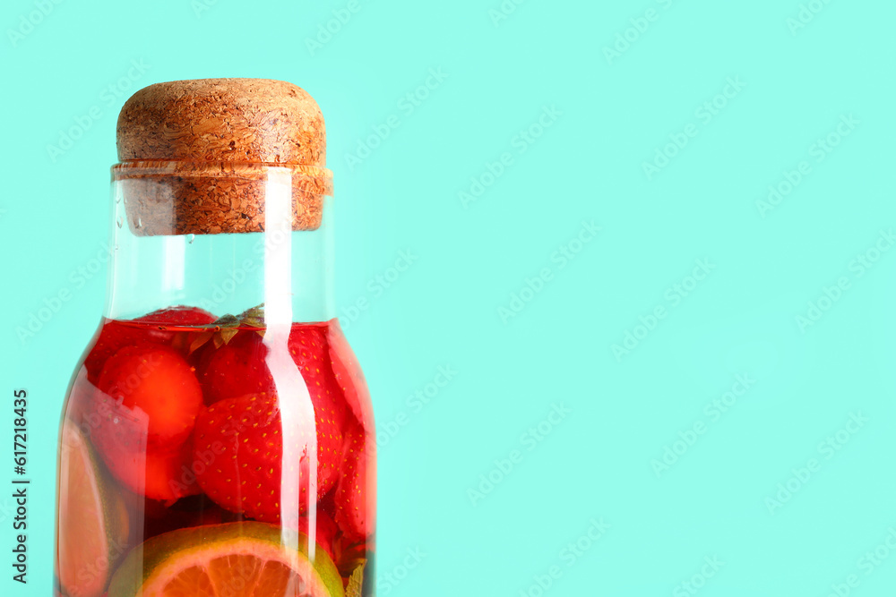 Bottle of infused water with strawberry and lime on blue background