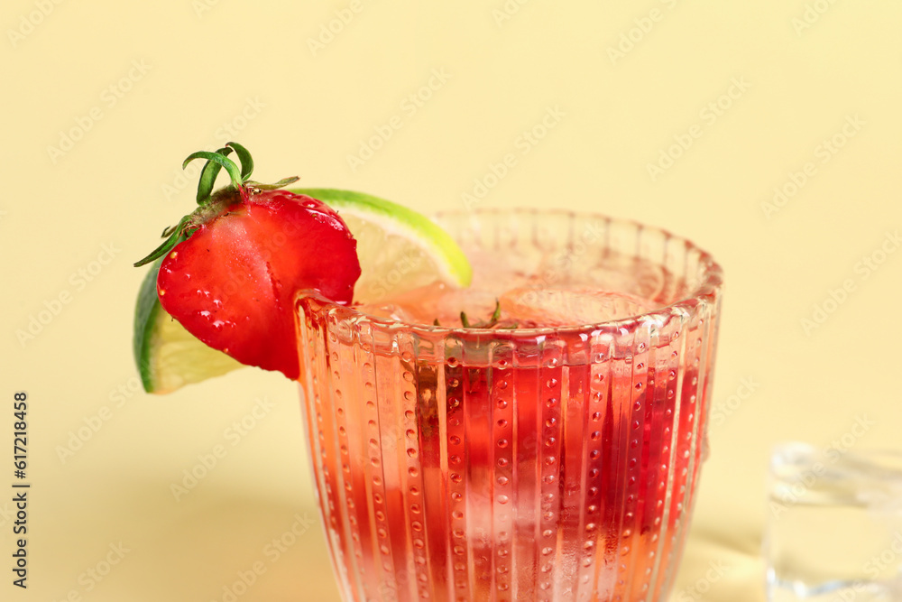 Glass of infused water with strawberry and lime on yellow background