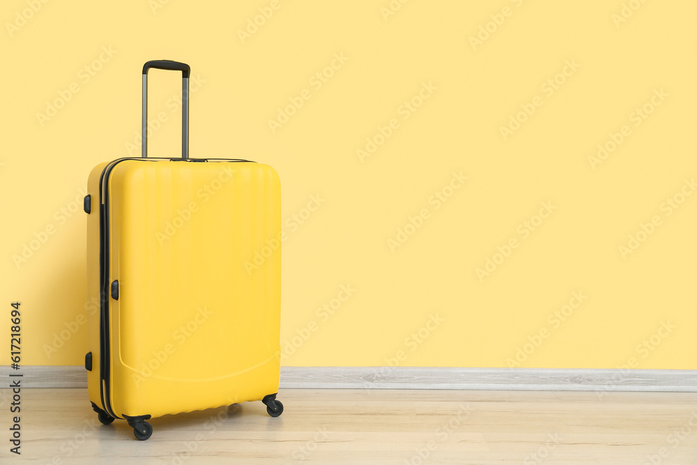 Suitcase near yellow wall. Travel concept