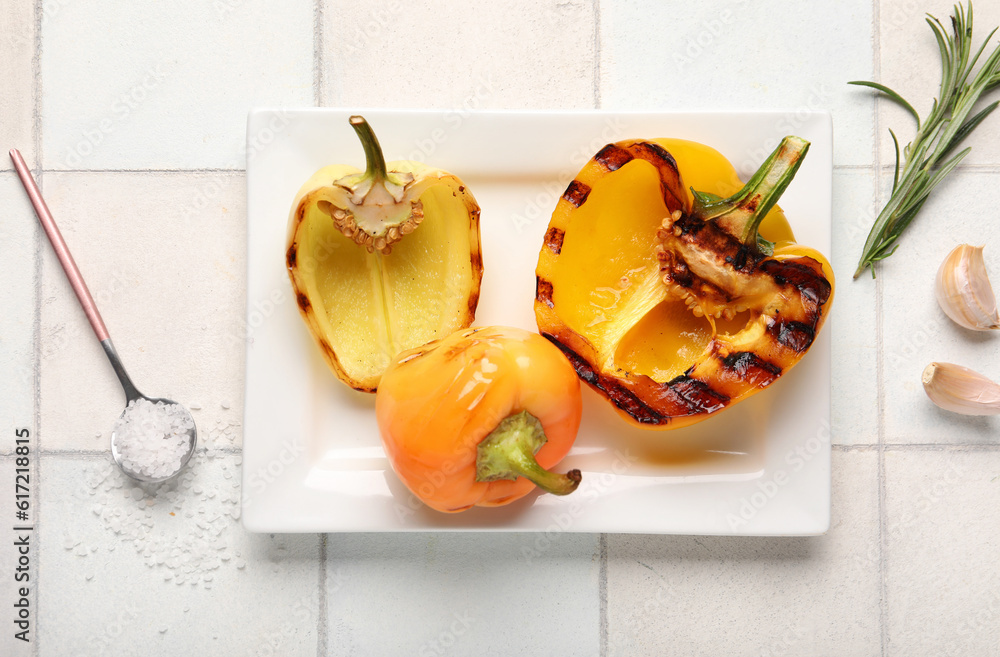 Plate with tasty grilled bell peppers on white tile background