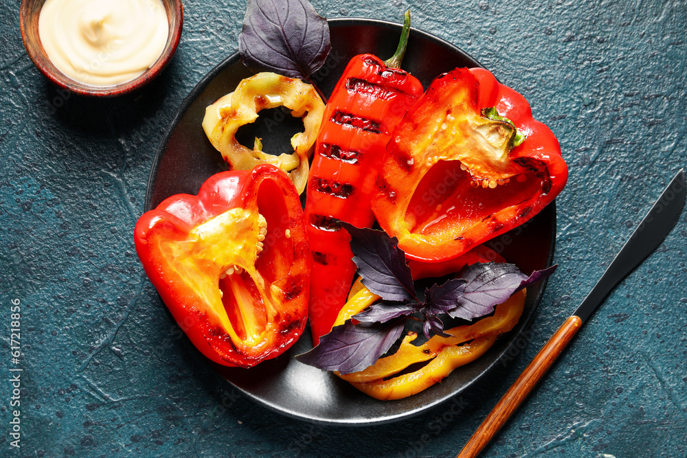 Plate with tasty grilled peppers on black background